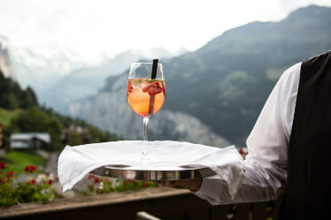 A waiter holding a wine glass on a tray.
