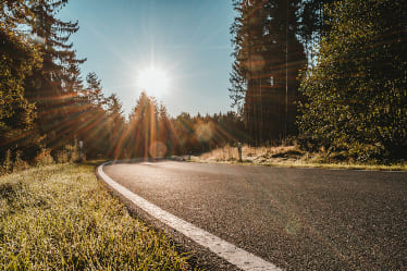 A sunny photo of a curved roadway.