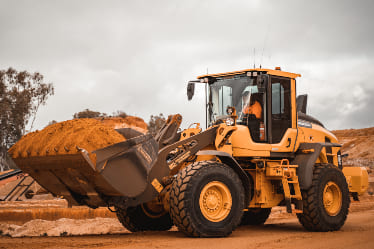 A yellow bulldozer holding dirt.